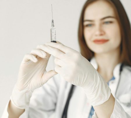 Smiling female doctor with gloves preparing a syringe for vaccination.