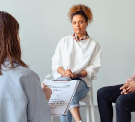 Counselor and diverse woman in a therapy session discussing mental health.