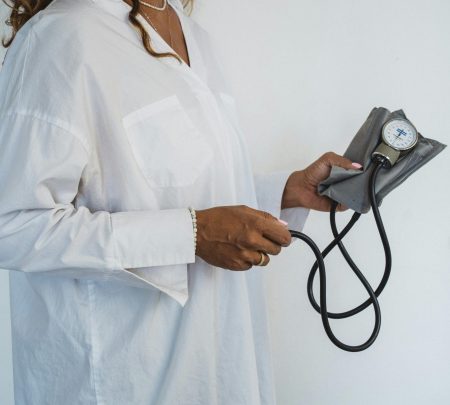 A healthcare professional in white holding a sphygmomanometer, demonstrating medical care.